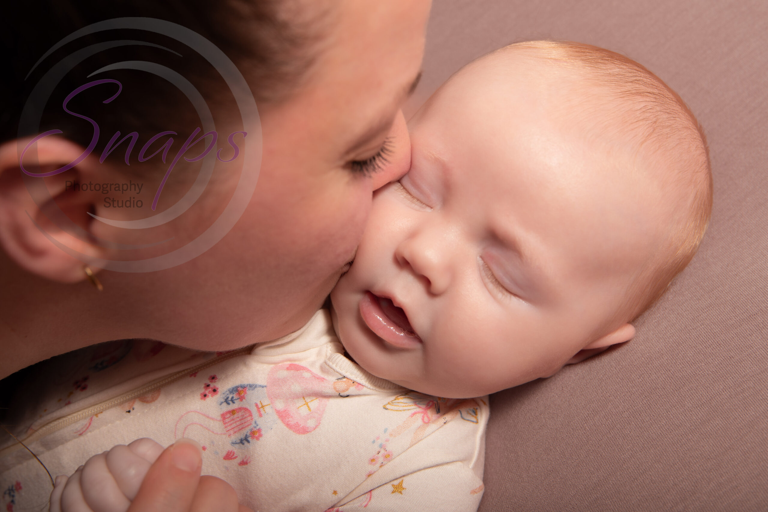 sleeping baby girl being kissed on the cheek by her mummy
