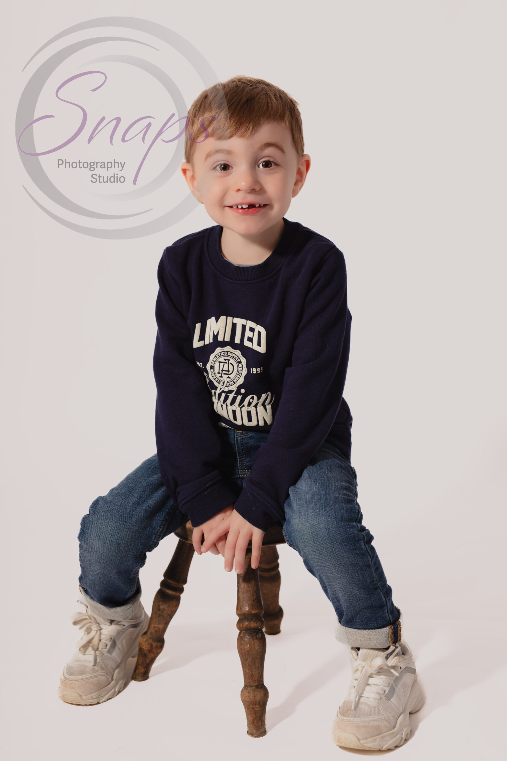 little boy sat on milking stool smiling