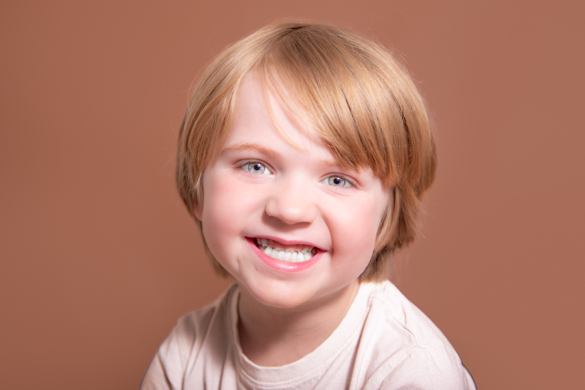 Smiling boy brown background having photoshoot in stroud