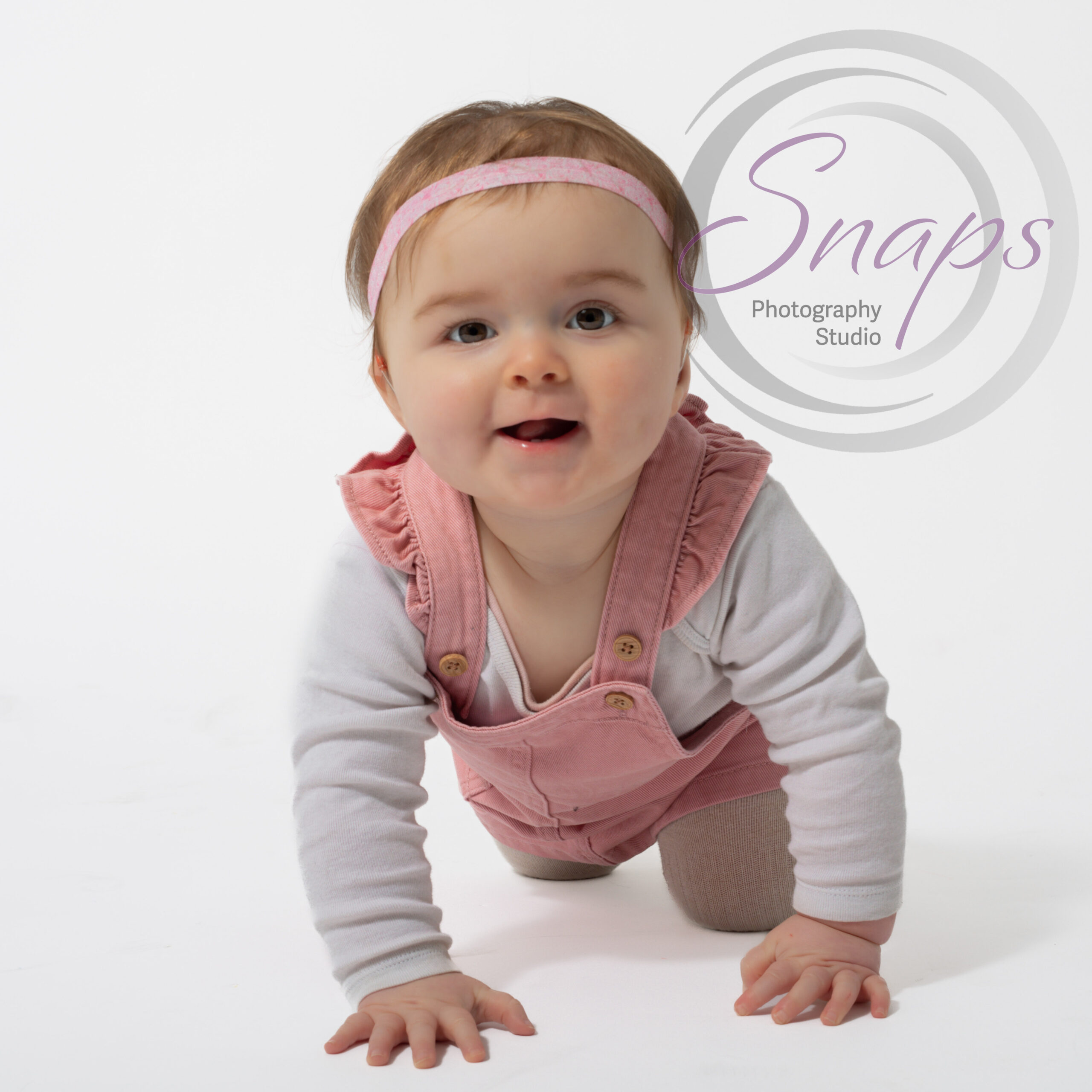 little girl on a white background wearing pink crawling to the camera